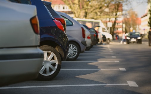 Parkende Autos in einer städtischen Straße bei Tageslicht, Seitenansicht mit Fokus auf Vorderrad eines Fahrzeugs